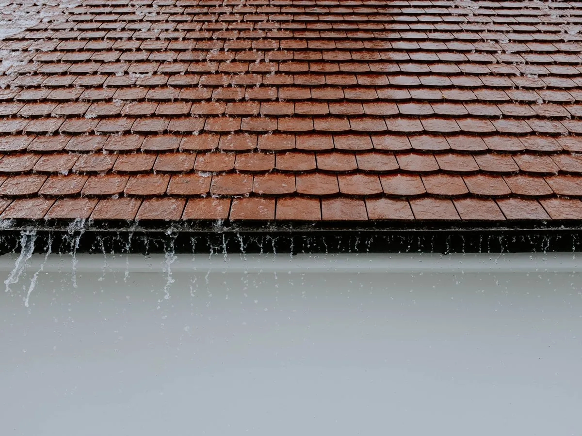 Eau de pluie ruisselant en nappe le long d’une toiture en tuiles plates